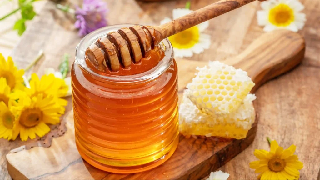 Honey in a glass jar with honeycomb