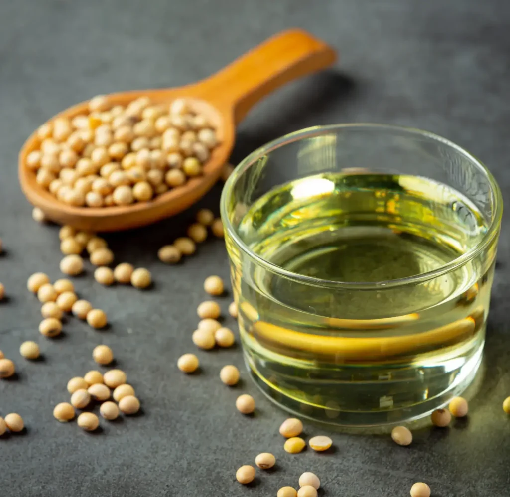 Refined soybean oil in a glass container beside soybeans