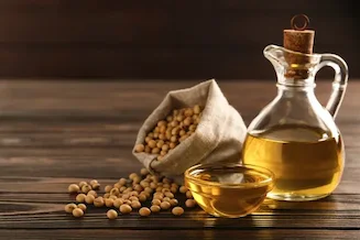 Soybean oil in a glass with soybeans on a wooden spoon